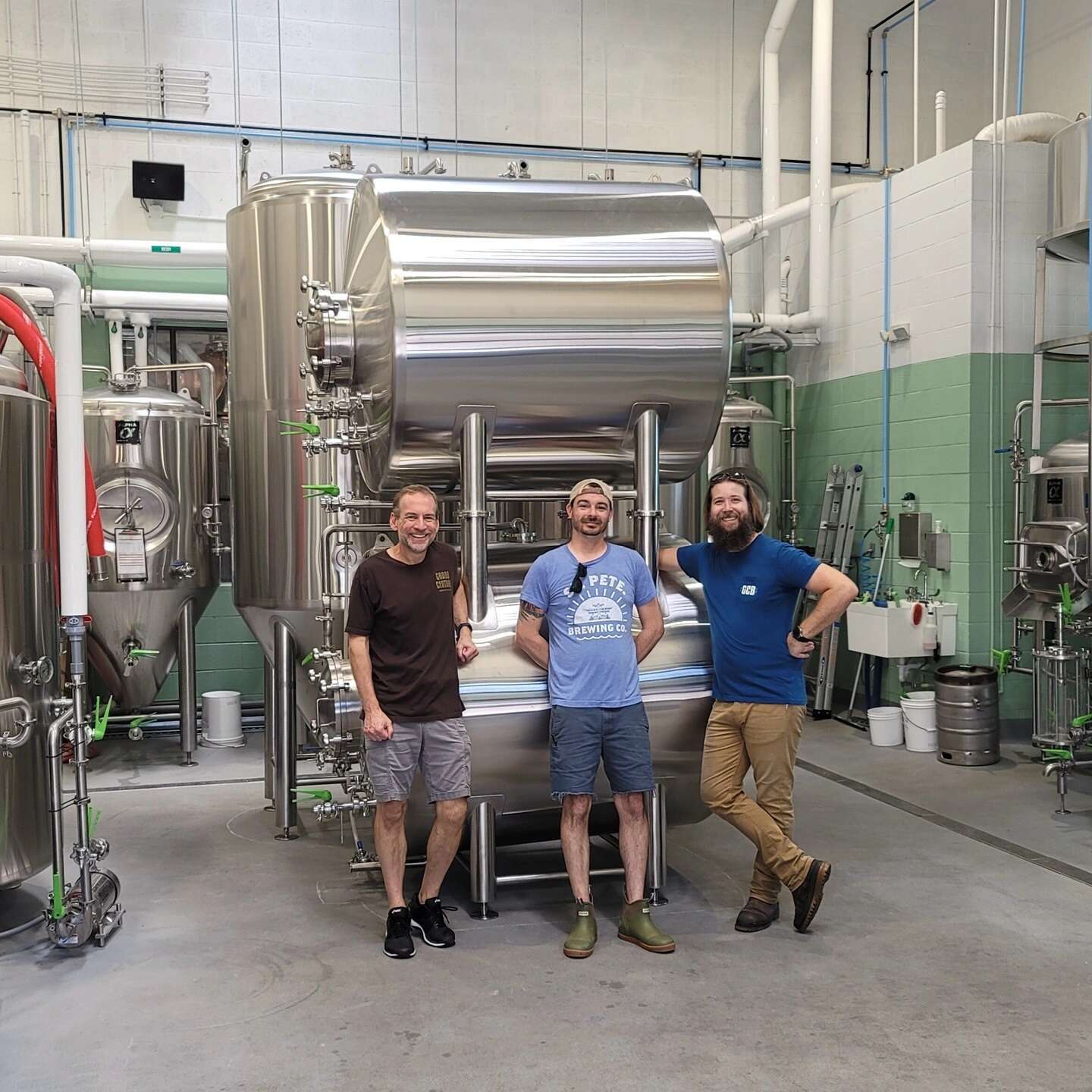 Brewery Owners and Brewers in front of Stainless Steel Horizontal, stacked brite tanks and vertical fermenters of varying sizes.