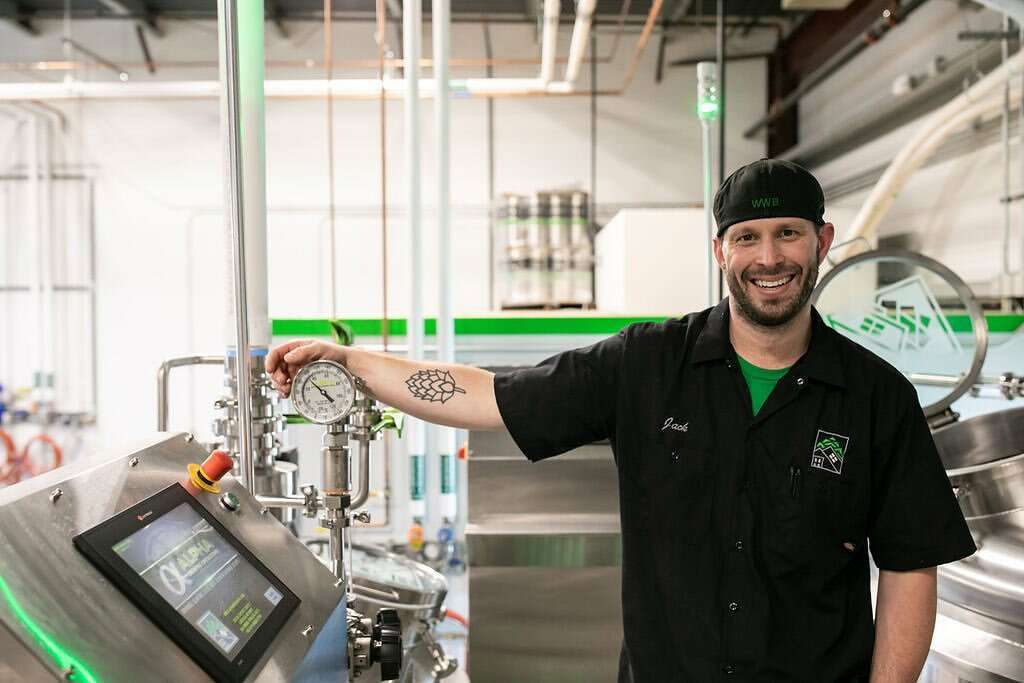 Pro Brewer standing in an Alpha Brewhouse while operating a full touchscreen automation