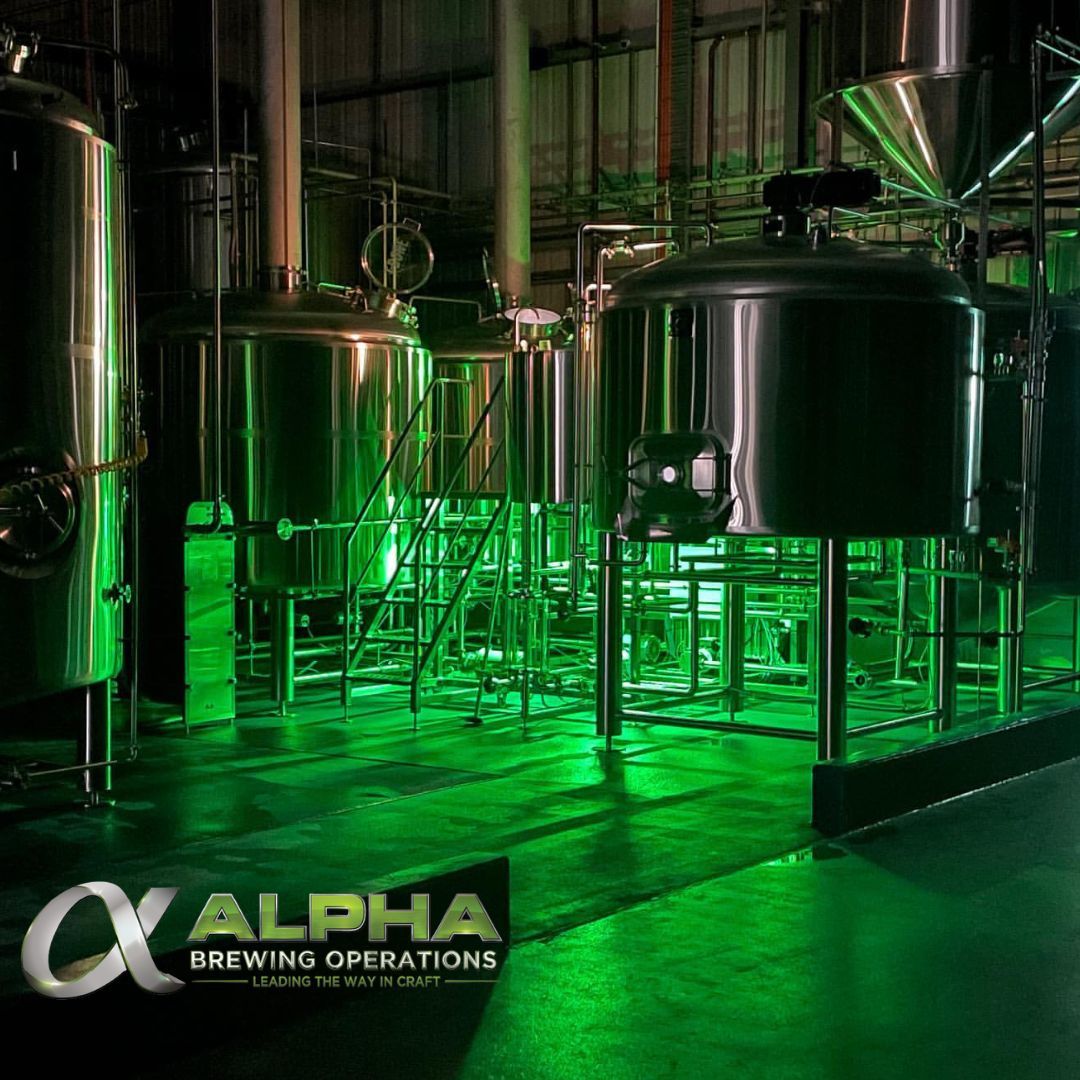 Stainless Steel 4-vessel Brewhouse with Platform, Mash Tun, Stainless Steel Whirlpool tank, Kettle, Vorlauf, hopper, and HLT Tank lit by green lights